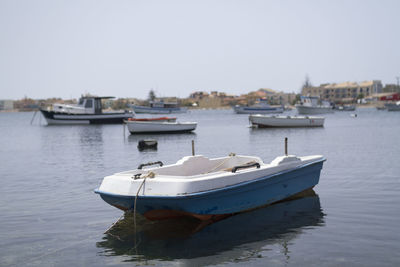 Boats moored at harbor against clear sky