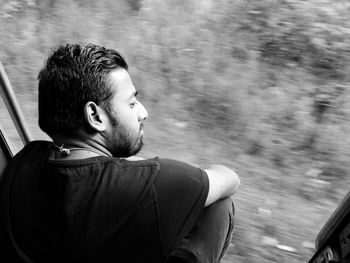 High angle view of thoughtful young man sitting at train doorway