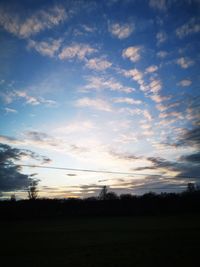 Silhouette trees on field against sky at sunset