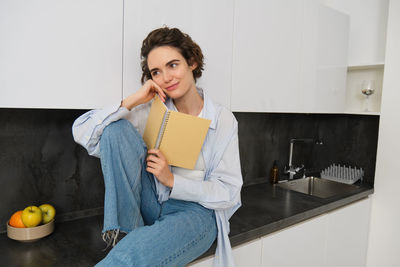 Young woman using phone while sitting at home