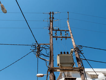 Low angle view of electricity pylon against clear blue sky