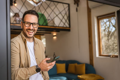 Portrait of young man using mobile phone at home