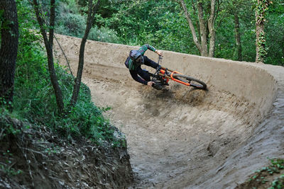 Male cyclist on bike for downhill riding along sandy path and performing extreme trick in woods