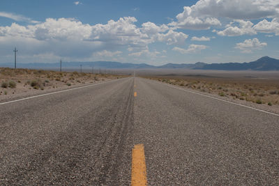 Empty country road amidst field against sky