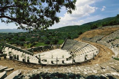 High angle view of old ruin amphitheater against cloudy sky