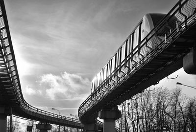 Low angle view of monorail on bridge against sky