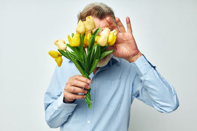 Senior man holding tulip against white background