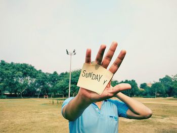 Midsection of person holding text against sky