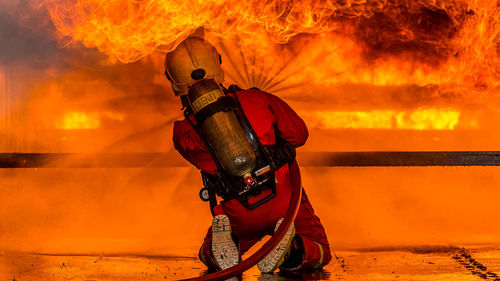 Rear view full length of firefighter spraying water