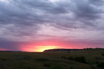 Scenic view of dramatic sky over land during sunset