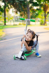 Portrait of girl holding push scooter on road