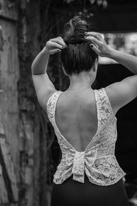 Rear view of woman with arms raised standing outdoors