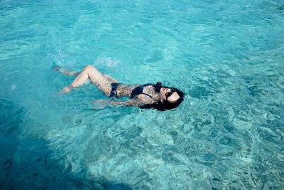 High angle view of woman swimming in a crystal clean ocean 