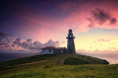 Lighthouse by sea against sky during sunset