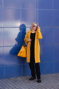 Portrait of young woman standing against wall