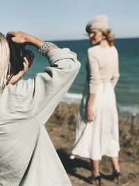 Rear view of woman photographing sea against sky