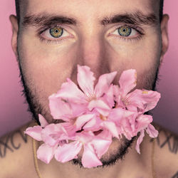 Close-up portrait of young man with pink flowers