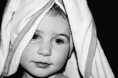 Close-up portrait of cute girl wearing towel against black background