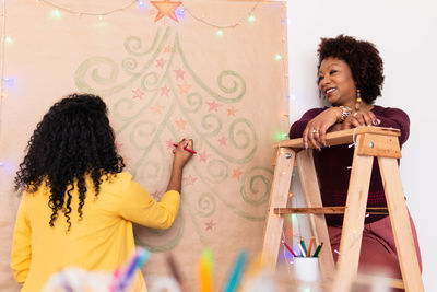 Smiling women standing by decorated wall at home