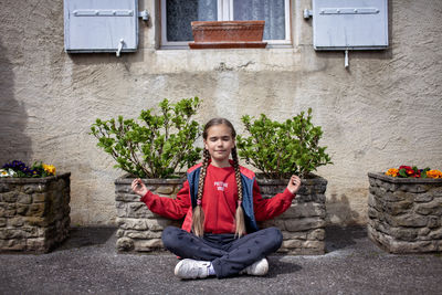 Portrait of young man sitting against wall