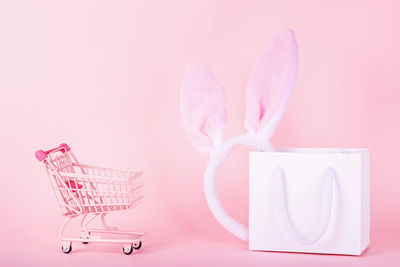 Mini shopping cart with bag against pink background