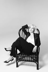 Portrait of woman sitting on chair against gray background