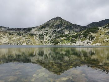 Scenic view of lake by mountain against sky