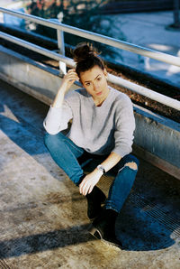 Portrait of young woman sitting on railing