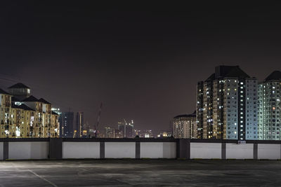 Illuminated buildings against sky at night