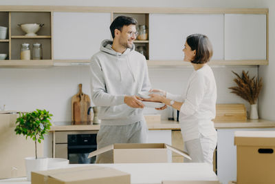 Smiling couple holding plates while standing at home