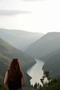 Rear view of woman standing on mountain against sky