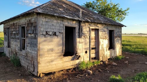 Abandoned house on field against sky