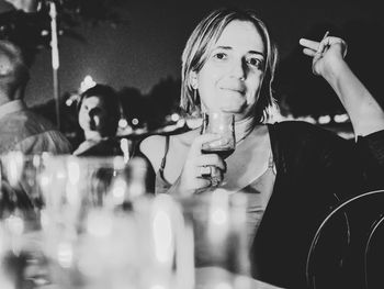 Portrait of woman holding drink while sitting at bar