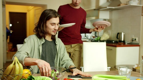 Happy friends standing by kitchen at home