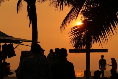 Rear view of silhouette people standing at beach during sunset