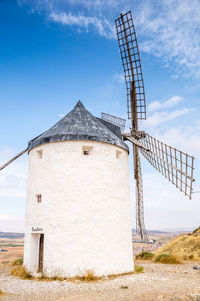 Traditional windmill on landscape against blue sky