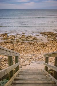 Staircase by sea against sky