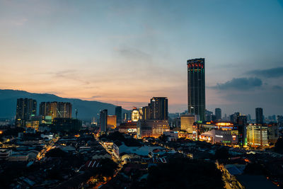 Illuminated buildings in city against sky during sunset