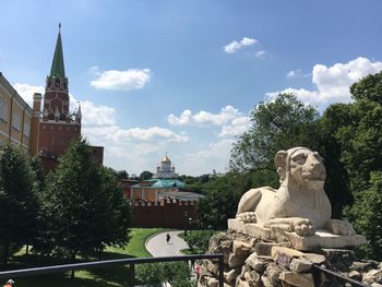 Statue amidst trees and buildings against sky