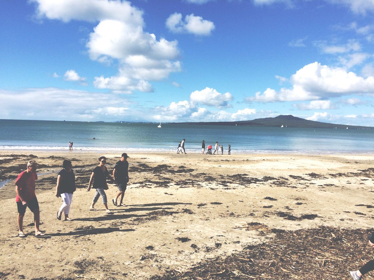 TOURISTS ON BEACH AGAINST SKY