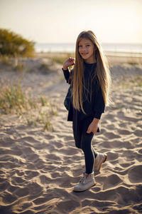 Portrait of a girl with long hair run on a sandy beach in a black leather jacket