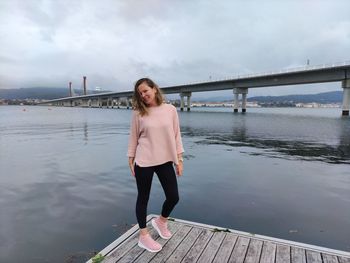 Full length portrait of woman standing on pier against sky