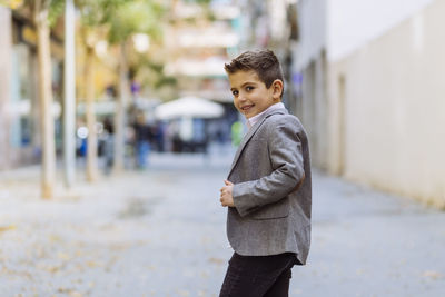 Portrait of boy standing on road in city