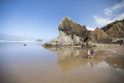 Woman standing on beach by sea against sky