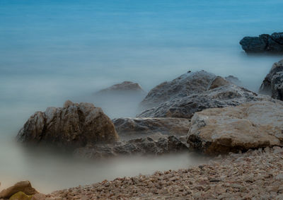 Scenic view of rocks on beach against sky