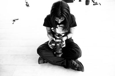 Young photographer sitting on the floor, checking his camera