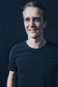 Portrait of young man standing against wall