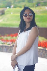 Portrait of young woman wearing sunglasses standing outdoors