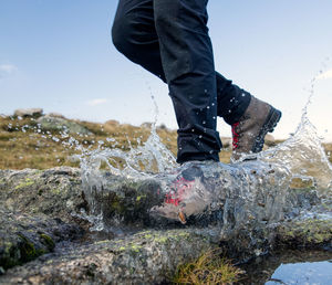 Low section of man standing on rock against sky