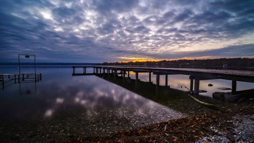 Pier over lake against sky during sunset